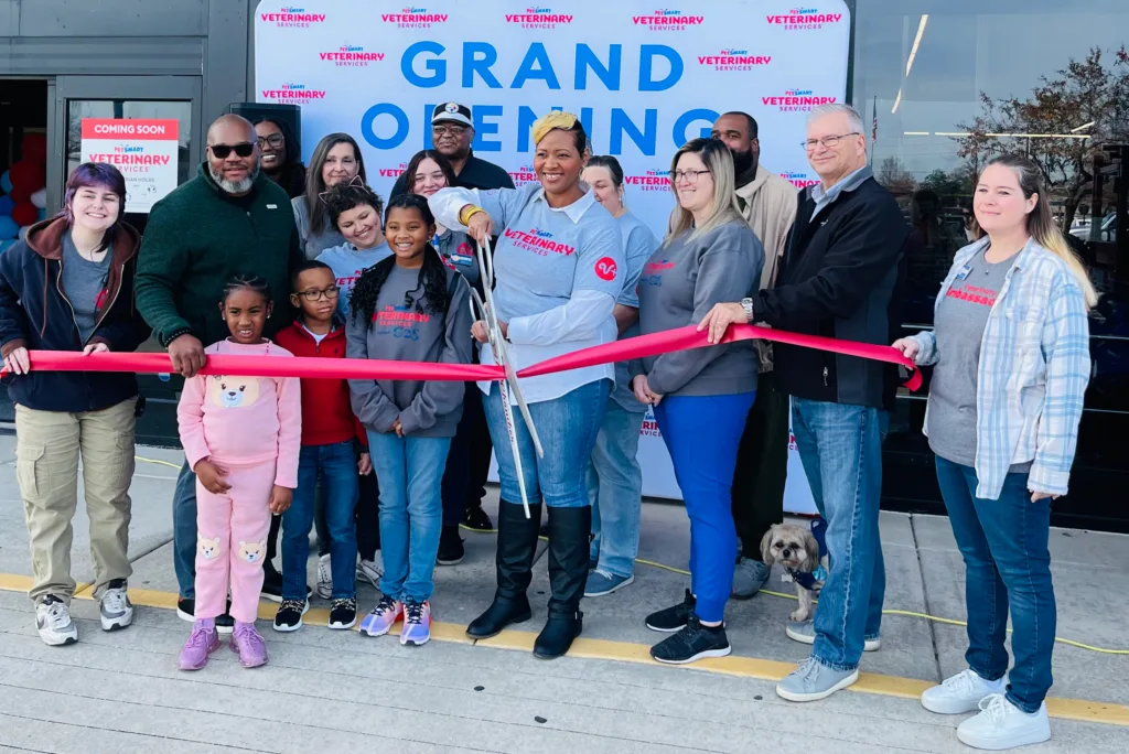 Ribbon cutting with the family in front of grand opening sign