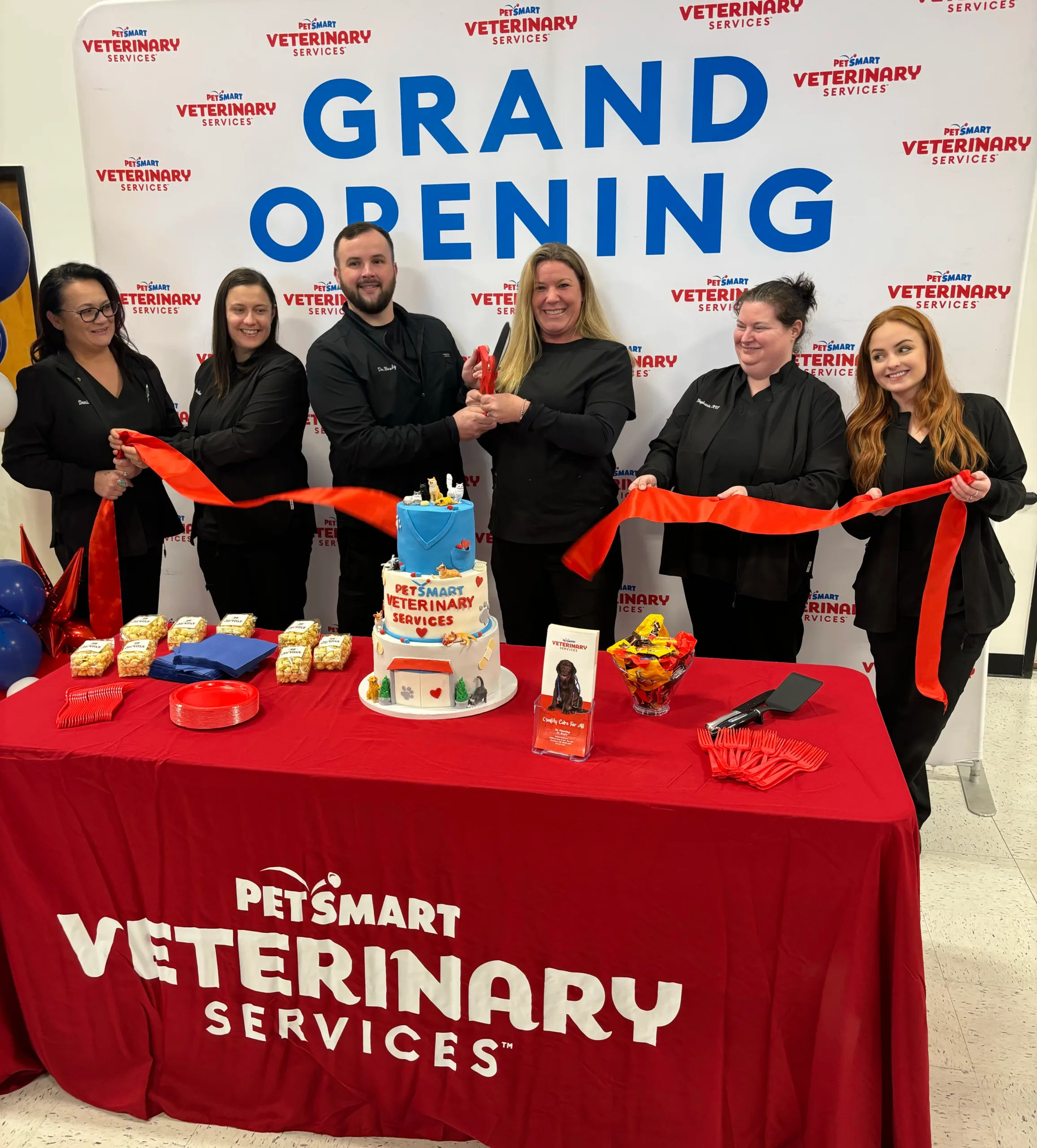 Team cutting ribon in front of grand opening banner