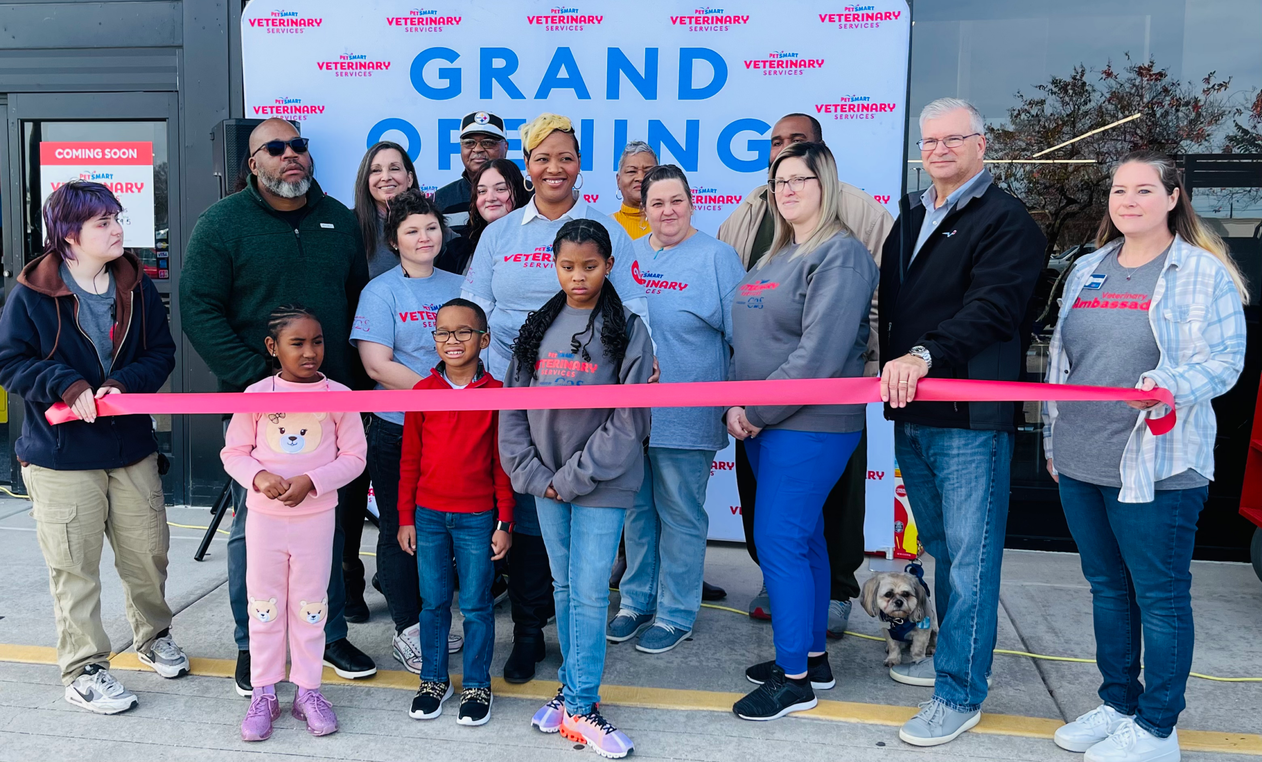 Ribbon cutting with the family in front of grand opening sign